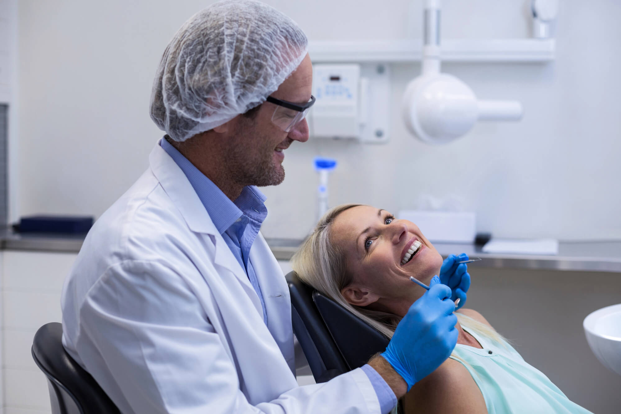 Doctor choosing tooth implants with female patient in modern dental clinic